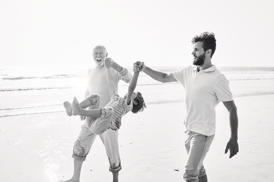 Happy grandfather, father and son on the beach 