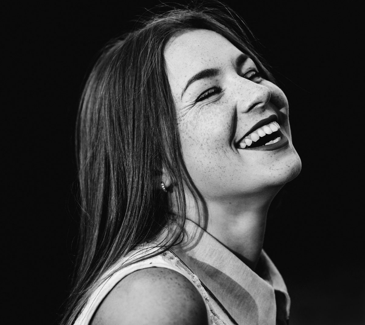 Black and white depiction of a woman laughing heartily with her eyes closed